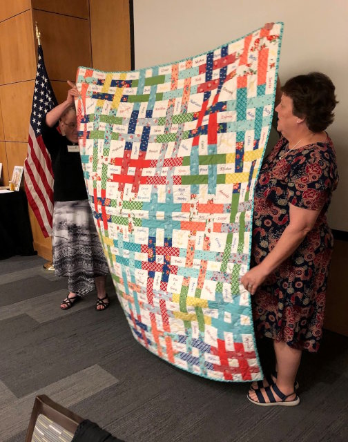 Two woman holding up a quilt