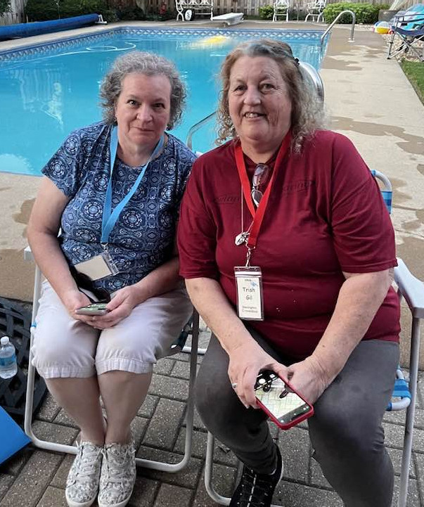 Two women posing in front of a pool