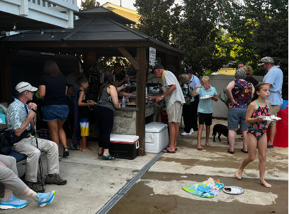Heaps of people getting food and drinks by an outside pool
