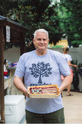 A gray-haired man holding a Huntley cake