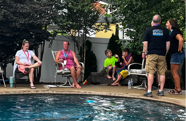 Several Huntley standing and sitting near the edge of a pool chatting