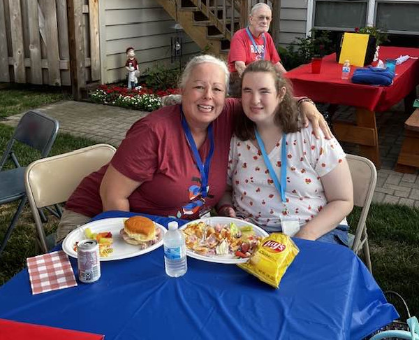 Two woman eating lunch stop to pose for a photo