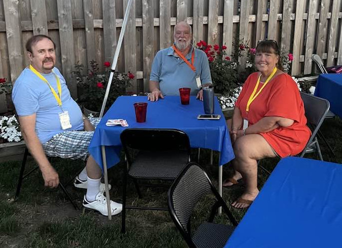 Three characters drinking around a table