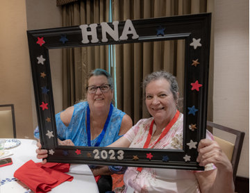 Two more women pose with the frame